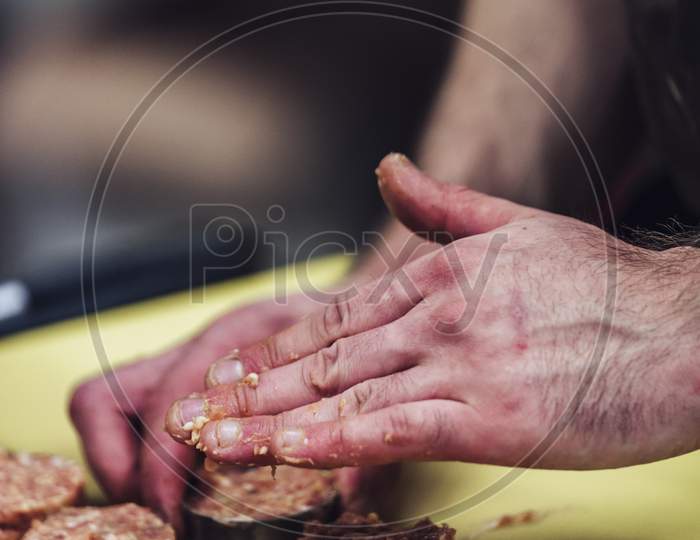 Male Chef Hands Making Round Pork Cutlets On Yellow Cutting Board