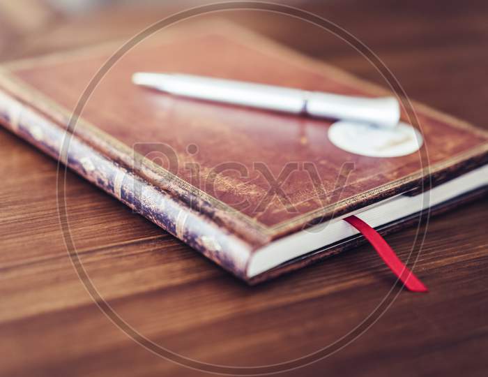 Antique Brown Notebook On Wooden Table With White Pen, Selective Focus