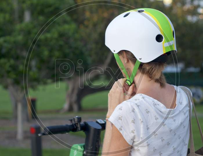 Woman Lacing A Helmet Before A E-Scooter Ride