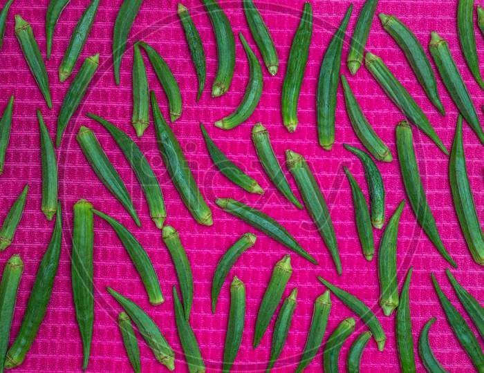 Green Lady Fingers Pattern From Top View, Okra Vegetable On Pink Cloth Background