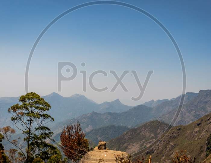 Single Rock With Hill Range And Blue Background