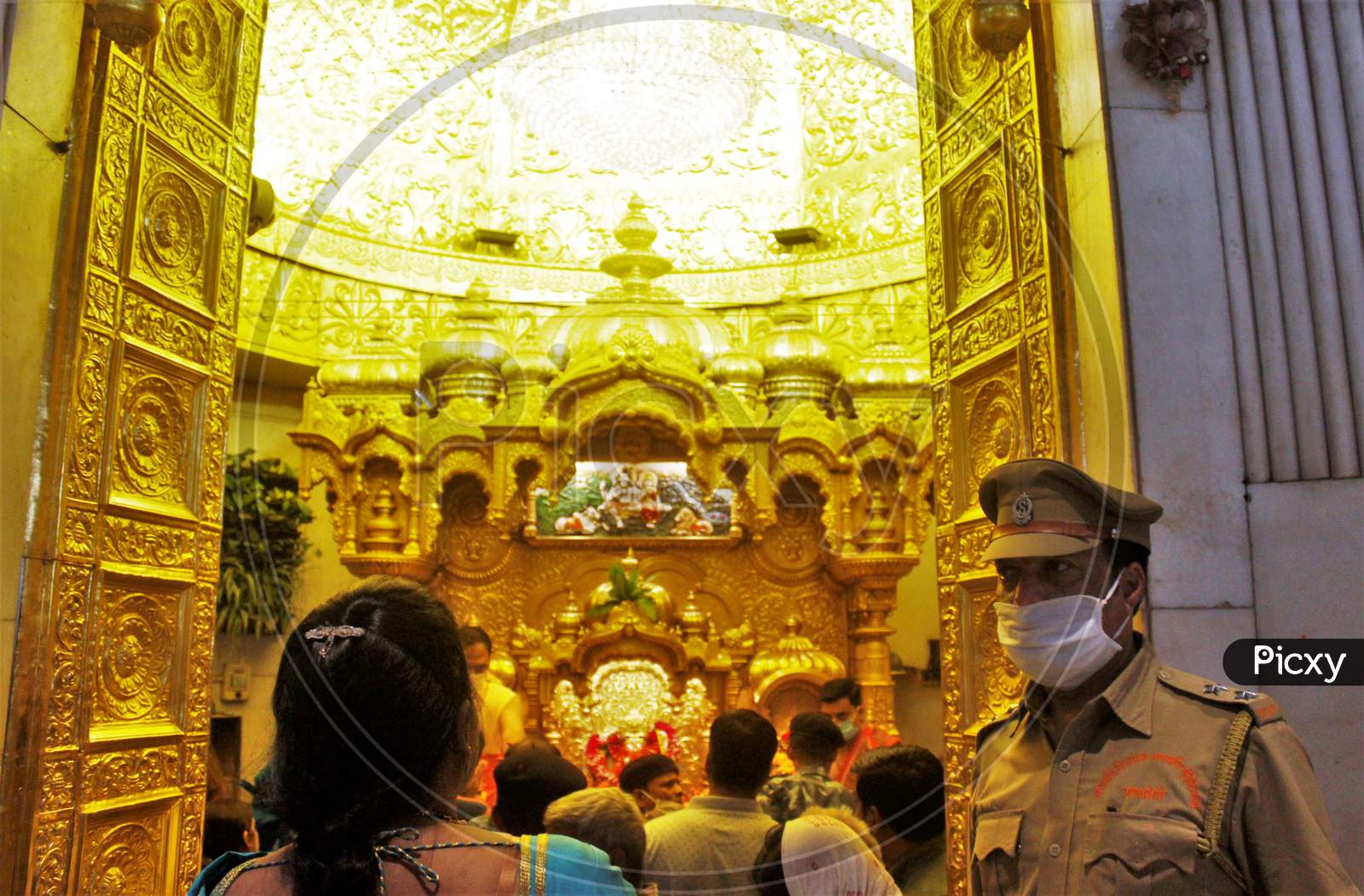 A security officer wearing a protective mask stands guard inside a temple in Mumbai, India March 13, 2020.