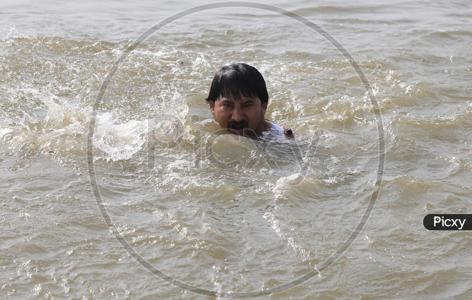 A Man  Taking Holy Bath In Triveni Sangam River on a Hot Summer Day During Extended Nationwide Lockdown Amidst Coronavirus Or COVID-19 Pandemic in Prayagraj, May 24,2020
