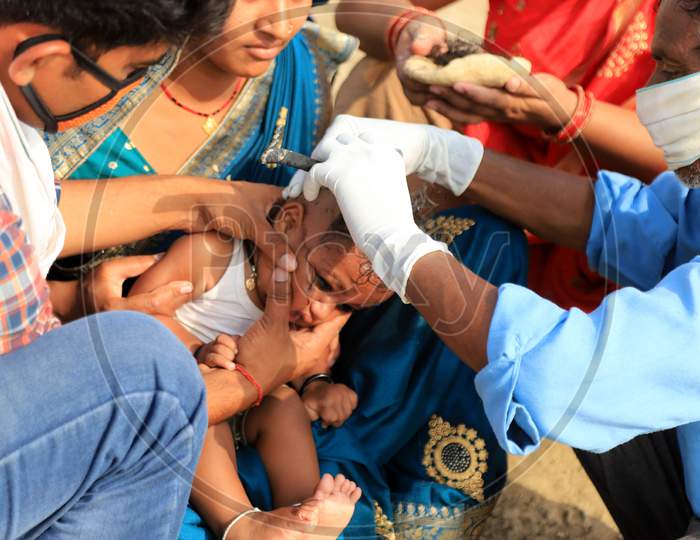 A Barber Saving Head Of A Child On The River Bank Of Ganga During Extended Lockdown  Amidst Coronavirus or COVID-19 Pandemic in prayagraj on May 24,2020