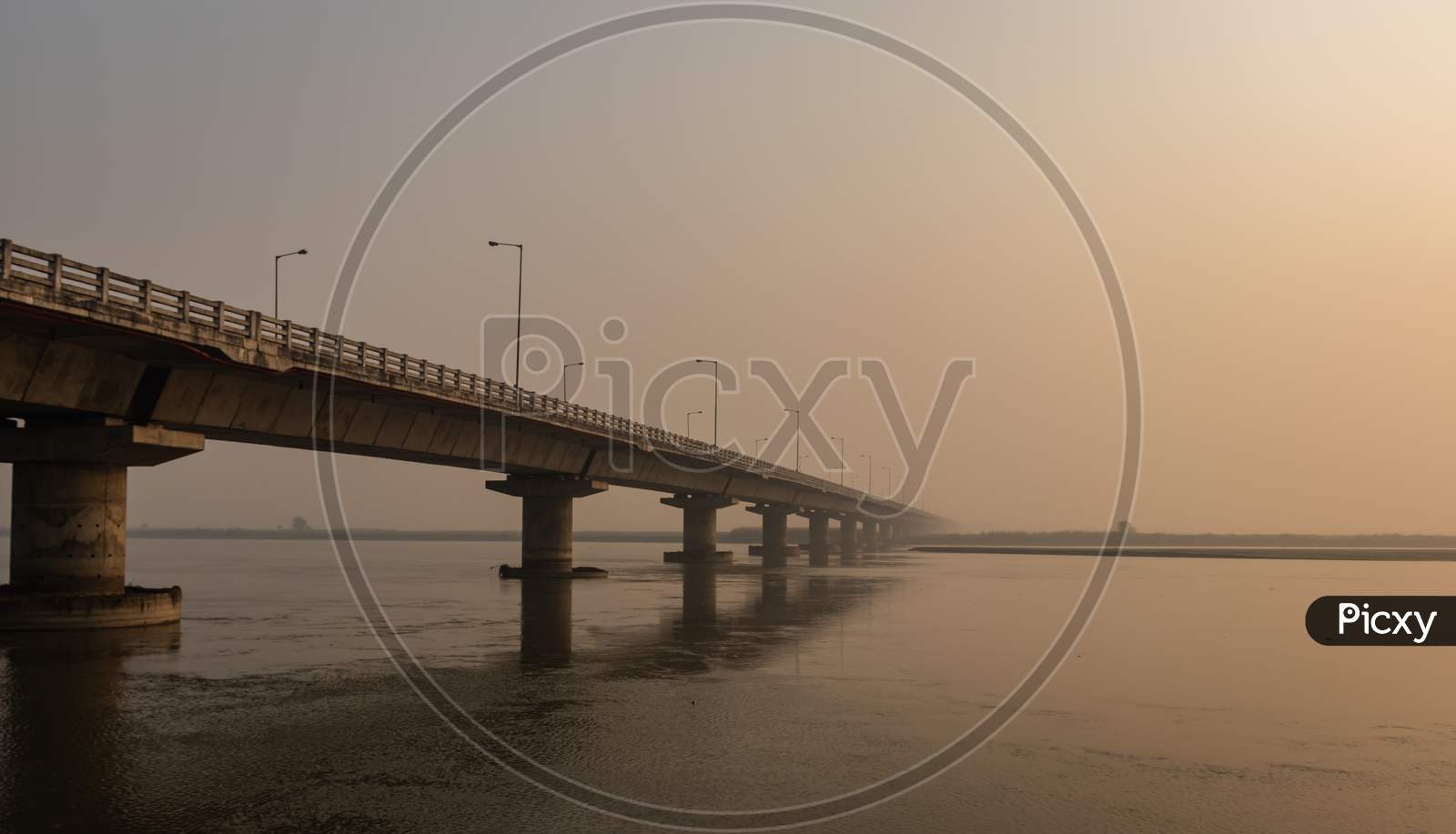 Road Bridge Over River With Its Water Reflection At Dawn From Low Angle