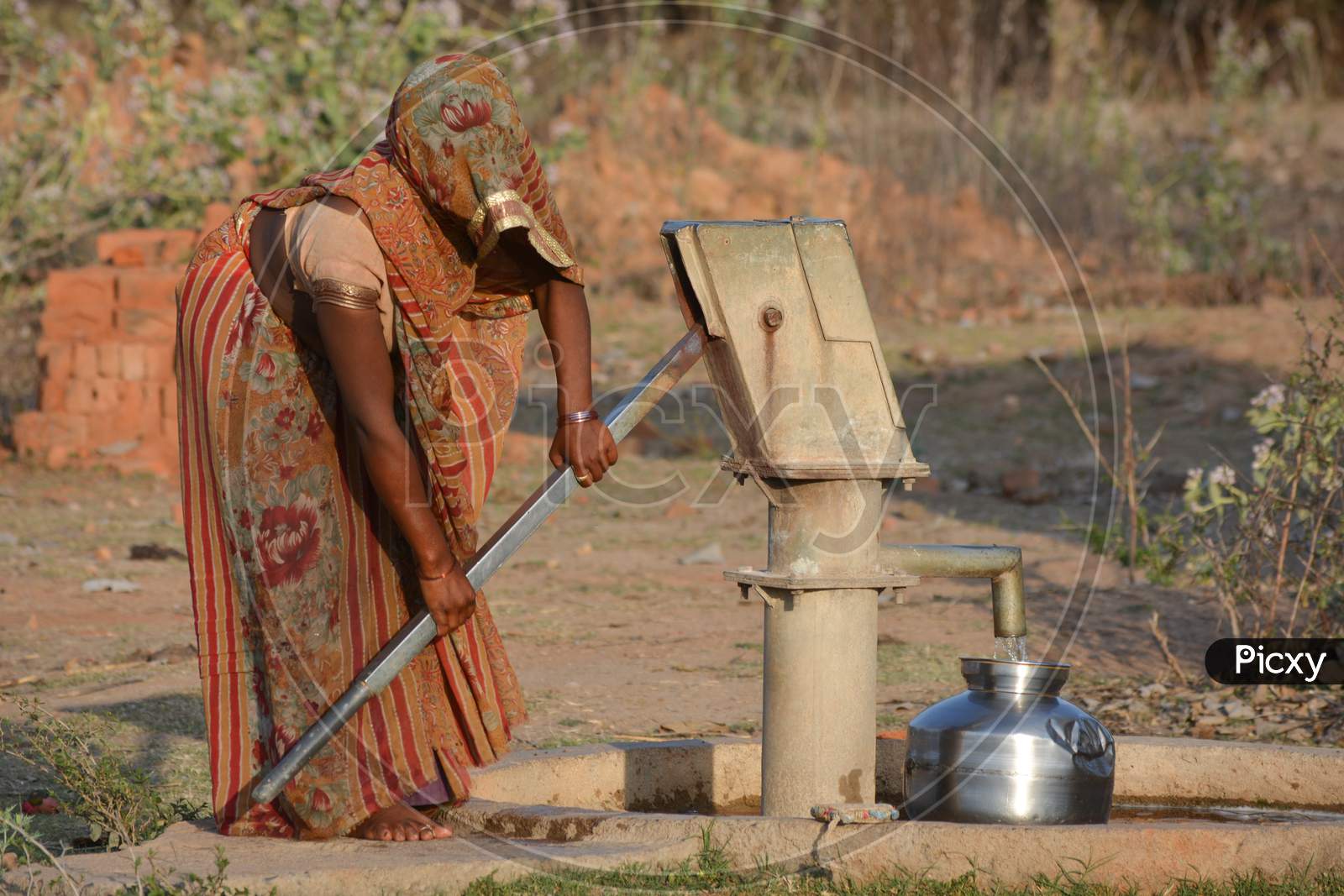 TIKAMGARH, MADHYA PRADESH, INDIA - MARCH 24, 2020: Unidentified Indian woman using hand pump for drinking water.