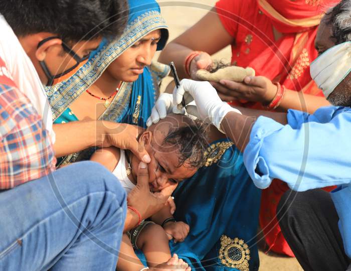 A Barber Saving Head Of A Child On The River Bank Of Ganga During Extended Lockdown  Amidst Coronavirus or COVID-19 Pandemic in prayagraj on May 24,2020
