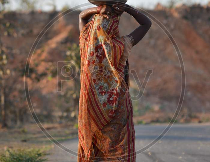 An Indian woman carrying a container of water on her head