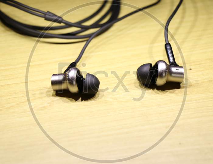 Earphones With Shiny Silver Speaker Body On Wooden Background