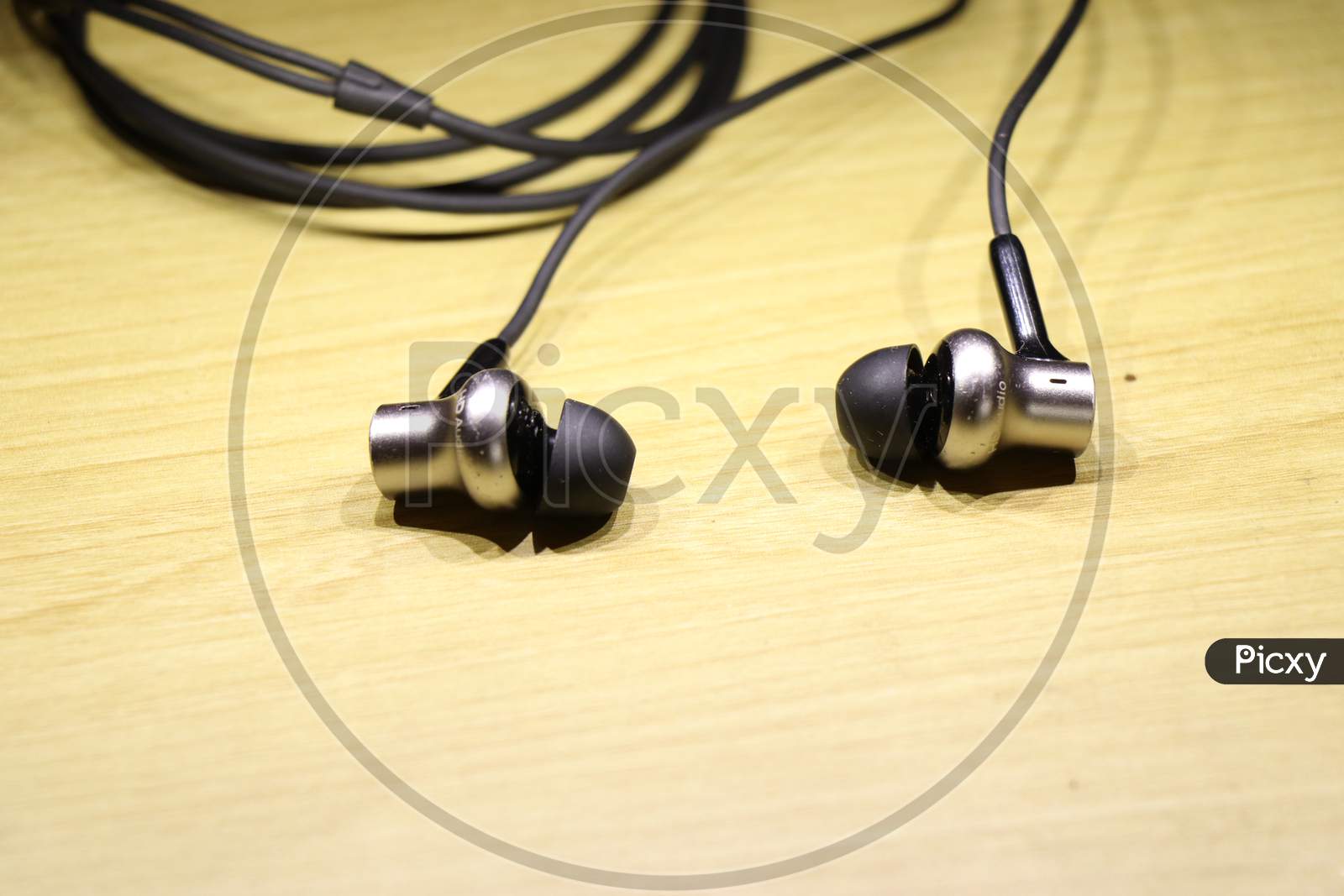 Earphones With Shiny Silver Speaker Body On Wooden Background