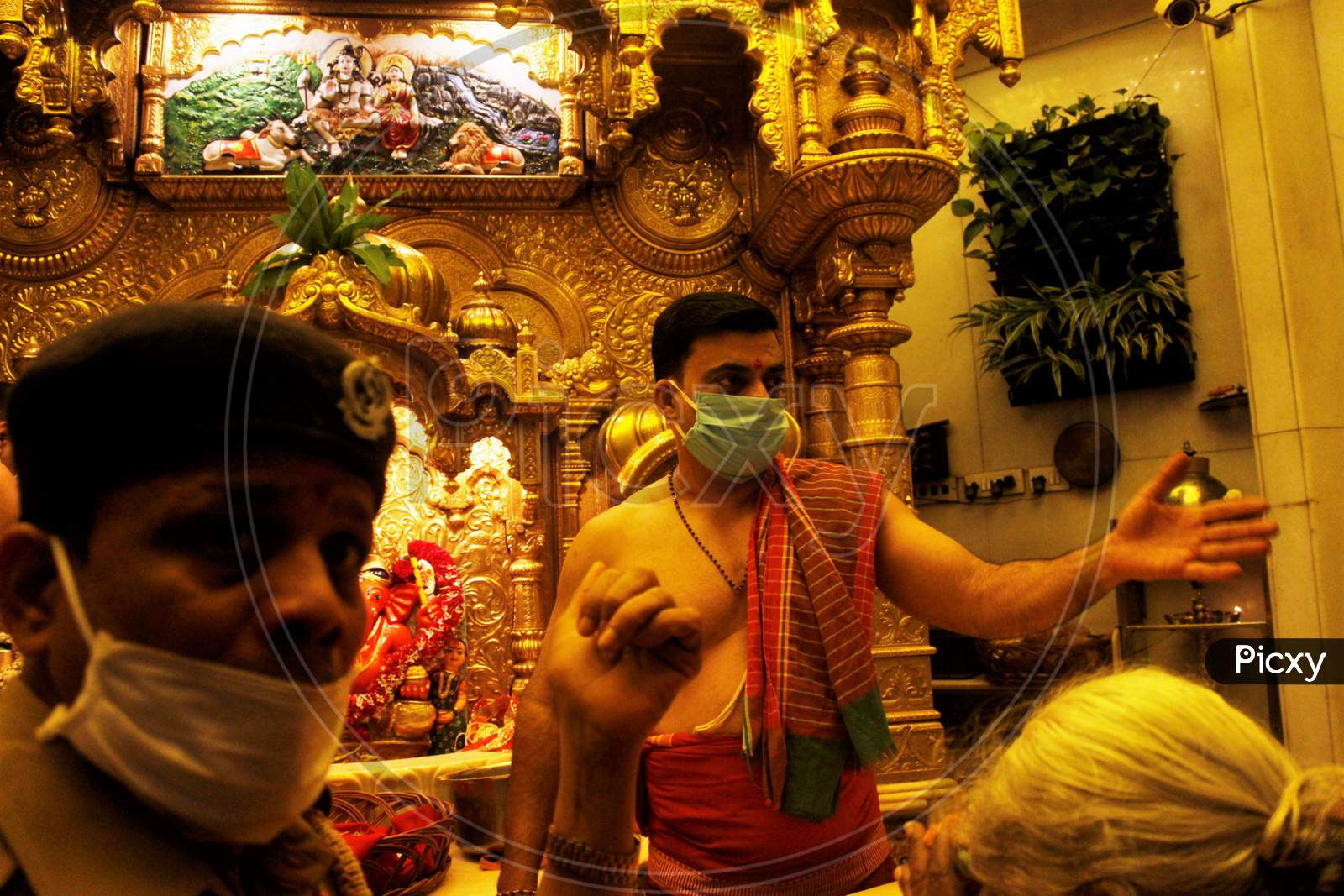 A security officer and a hindu priest  wearing protective masks are seen inside a temple in Mumbai, India March 13, 2020.