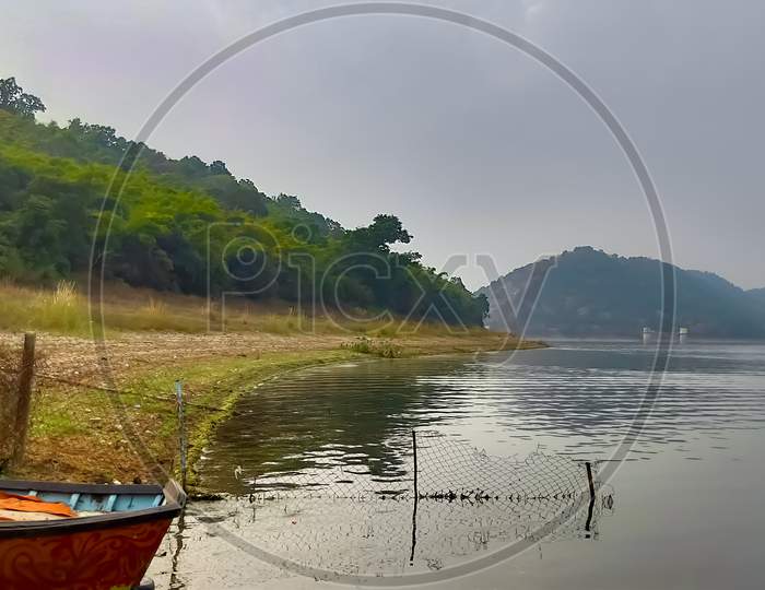 Fishing boat on water bank. A boat stands near the lake. Beautiful scenery of a lake mountain and a boat.