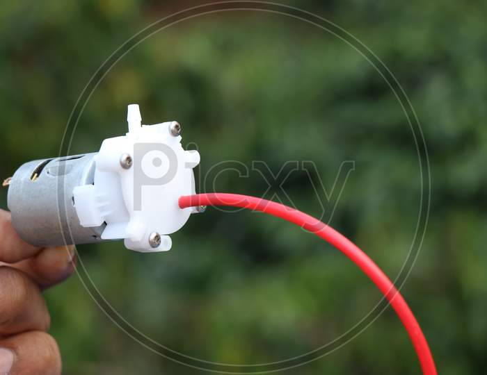 Small Dc Motor Powered Water Pump With Small Tubes Held In Hand