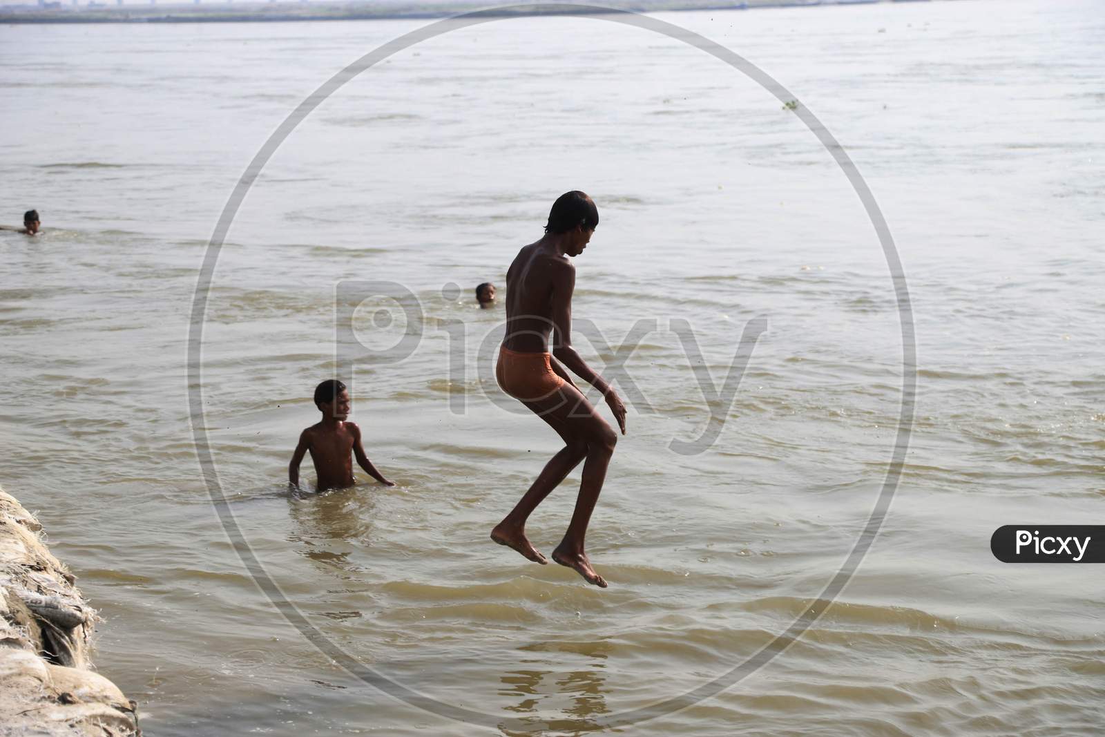 A Boy Jumping and Taking bath  In Triveni Sangam River on a Hot Summer Day During Extended Nationwide Lockdown Amidst Coronavirus Or COVID-19 Pandemic in Prayagraj, May 24,2020