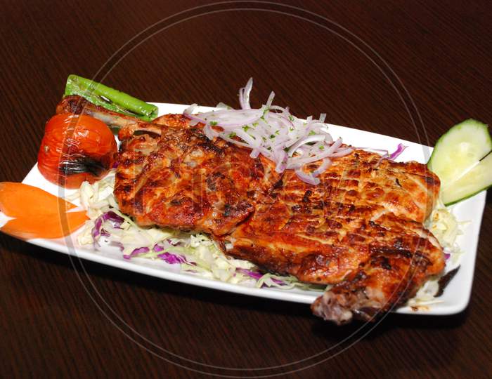 Grilled Half A Chicken On The Plate With Onion And Vegetables