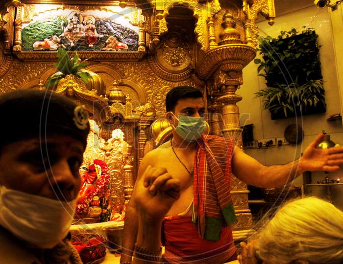A security officer and a hindu priest  wearing protective masks are seen inside a temple in Mumbai, India March 13, 2020.