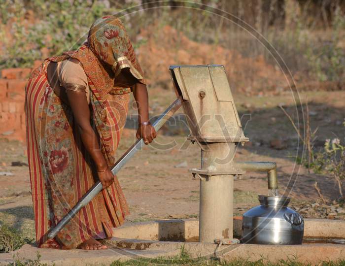 TIKAMGARH, MADHYA PRADESH, INDIA - MARCH 24, 2020: Unidentified Indian woman using hand pump for drinking water.