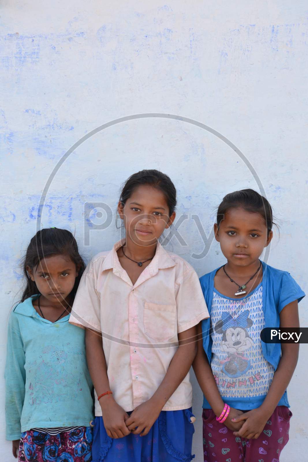 TIKAMGARH, MADHYA PRADESH, INDIA - MARCH 24, 2020: Group of happy Indian little village girls standing in front of their house.