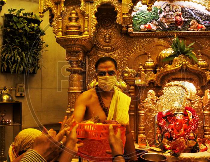 A Hindu priest wearing a facemask amid concerns over the spread of the COVID-19, is seen at a temple in Mumbai on March 13, 2020.