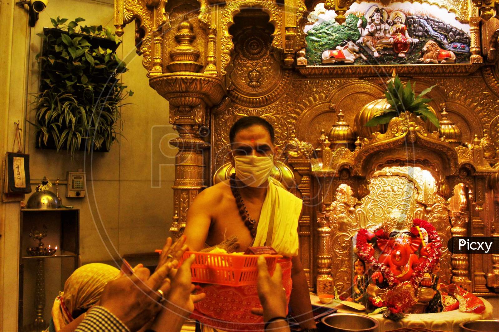 A Hindu priest wearing a facemask amid concerns over the spread of the COVID-19, is seen at a temple in Mumbai on March 13, 2020.