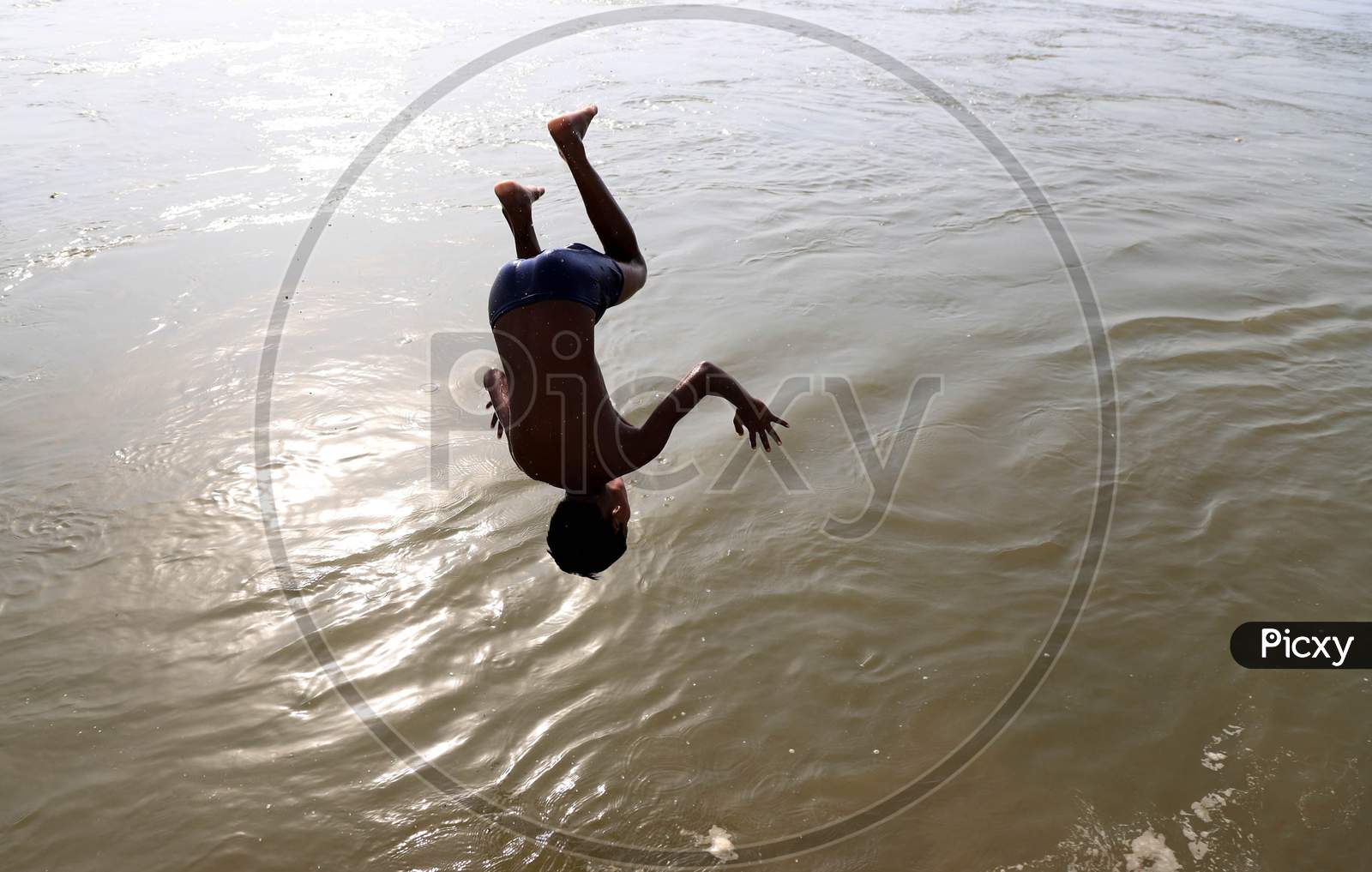 A Boy Jumping and Taking bath  In Triveni Sangam River on a Hot Summer Day During Extended Nationwide Lockdown Amidst Coronavirus Or COVID-19 Pandemic in Prayagraj, May 24,2020