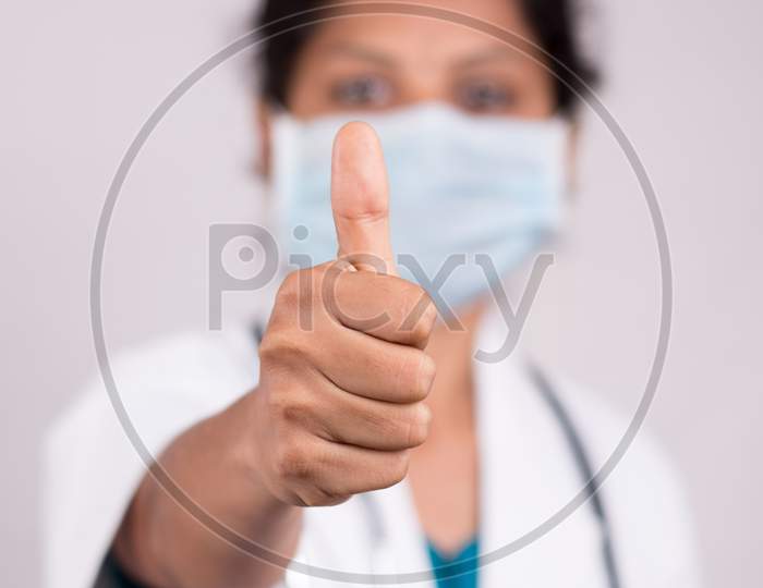 Woman Doctor With Medical Mask In Uniform Showing Thumbs Up On Isolated Background - Concept Of Approval Or Ok By Doctor During Covid-19 Or Coronavirus Pandemic.