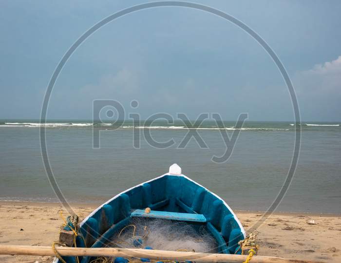 Fishing Boat With Fishing Net On The Yellow Sandy Beach With Clouds And Blue Sky