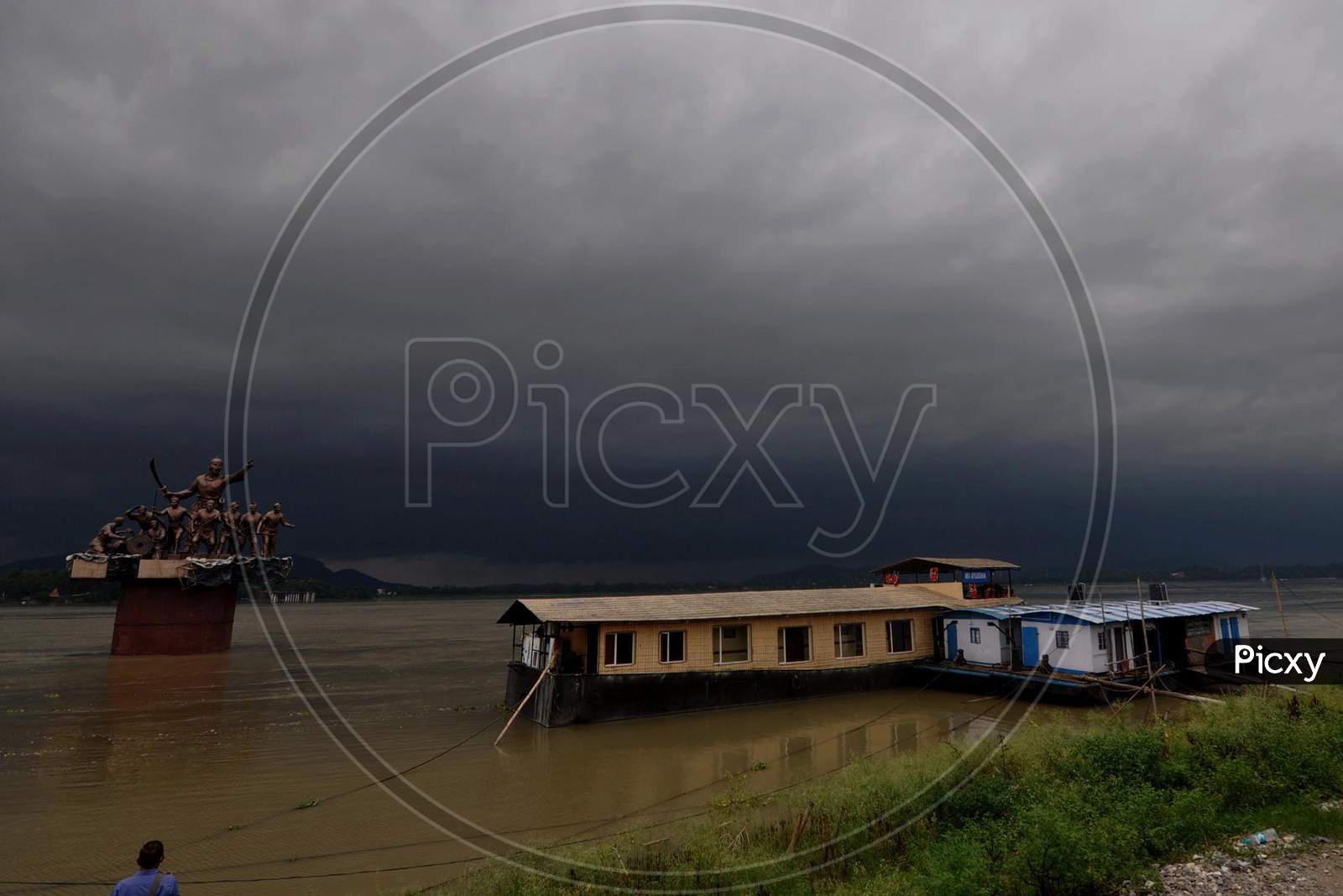 Dark Cloud Loom Over The Statue Of Ahom Lieutenant Lachit Borphukan Erected Over The River Brahmaputra In Guwahati On May 25, 2020.