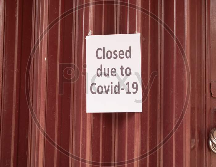 Closed Due To Coronavirus Or Covid-19 Signage On Closed Shutter Door In Front Of Shop Or Store Due To Coronavirus Outbreak.