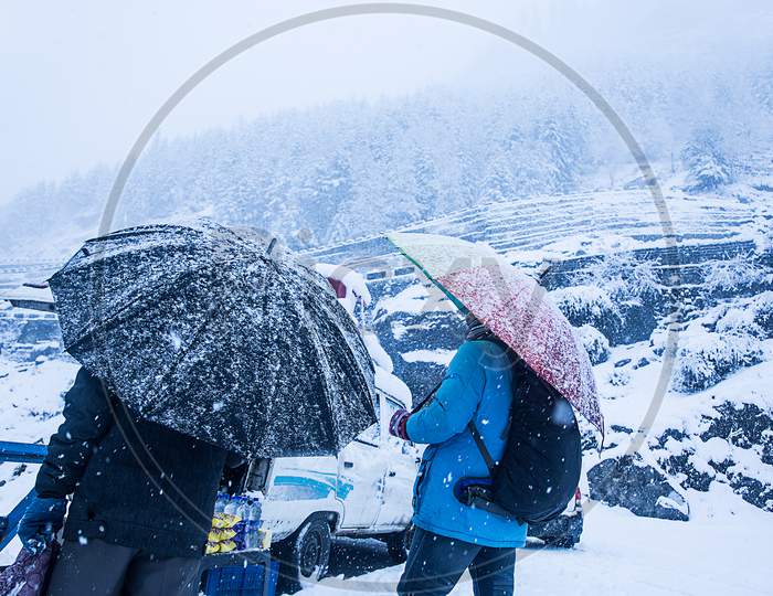 Two Guys With Umbrella Walking At Heavy Snowy Day In The Himachal. Snowfall Winter Concept, Wide Angle Shot - Image
