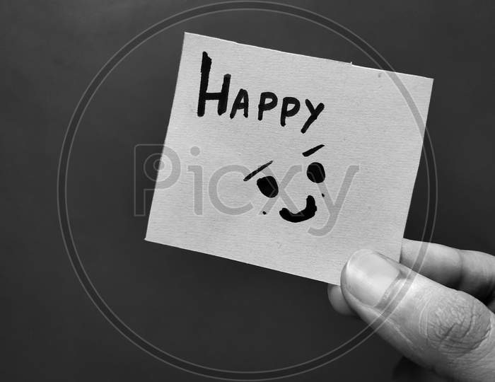 Hand holding a paper card with the word HAPPY