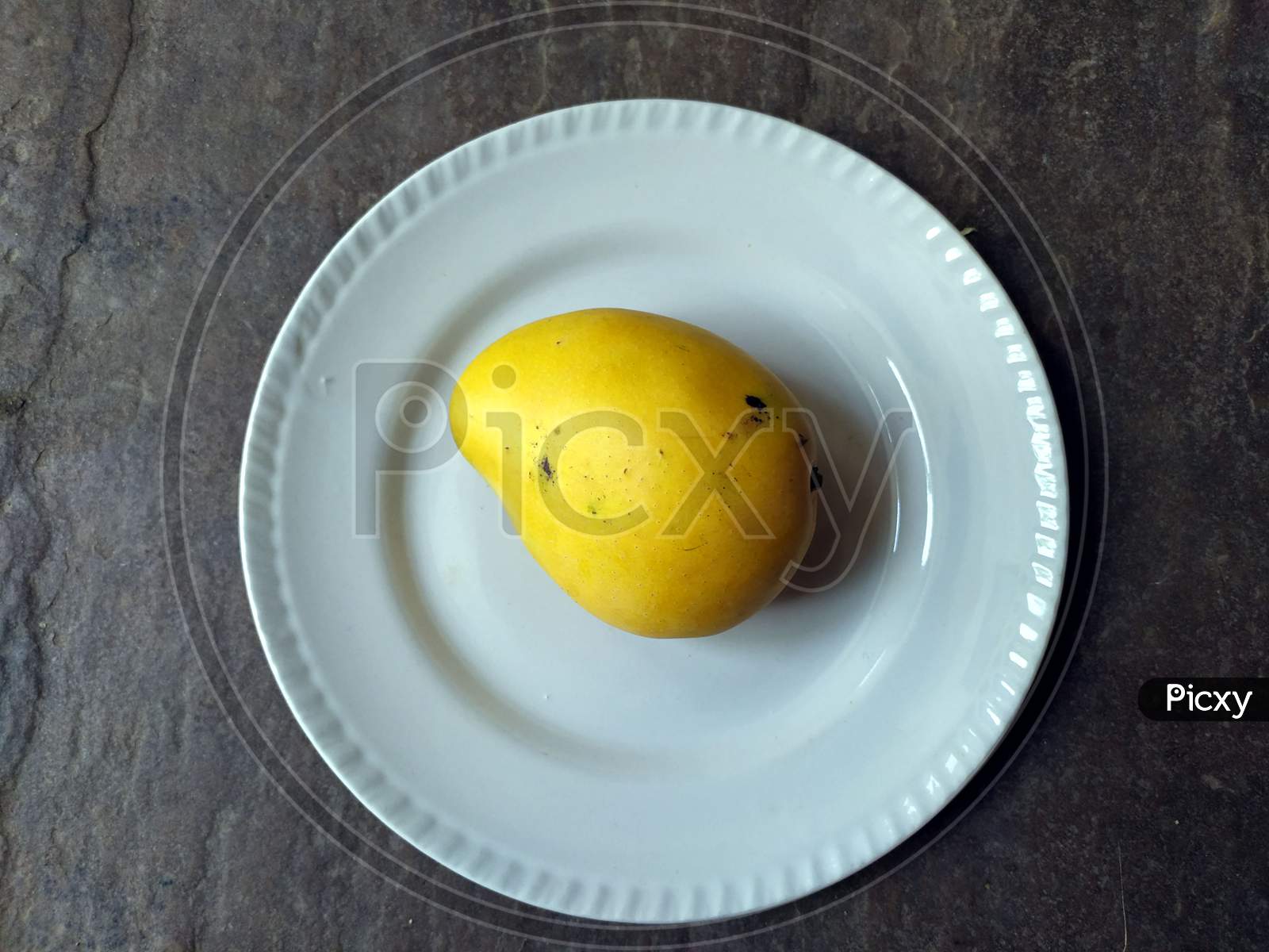 fresh sweet yellow mango put in a white plate on stone background