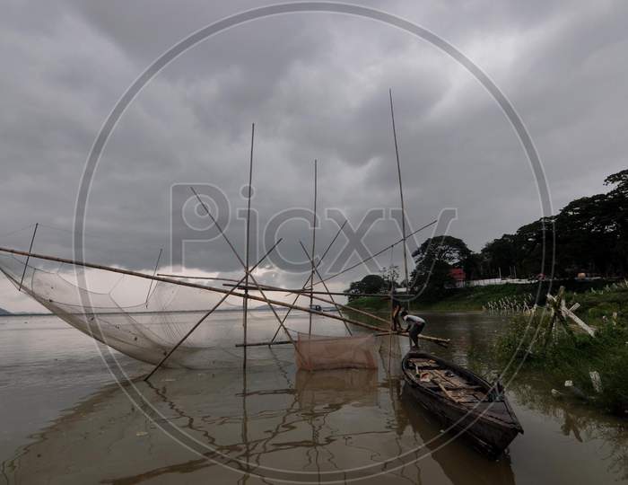 Fisherman Cast His Fishing Net As Dark Cloud Loom Over The Sky On The Bank Of The River Brahmaputra In Guwahati On May 25, 2020.
