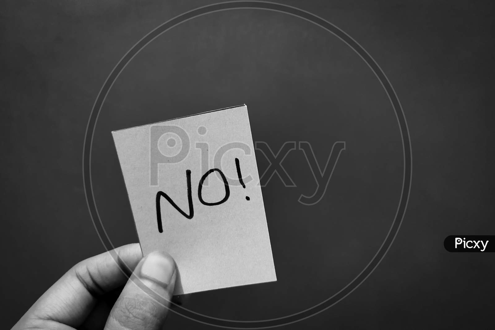 Hand holding a paper card with the word NO