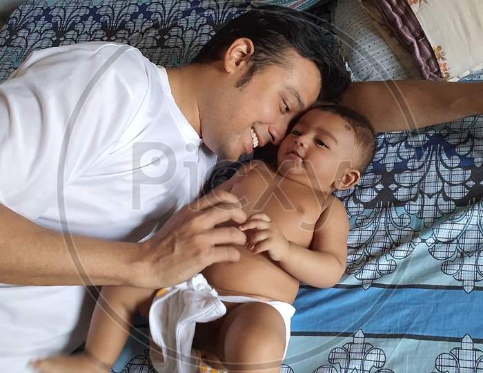 Father Cuddling His Baby On The Bed