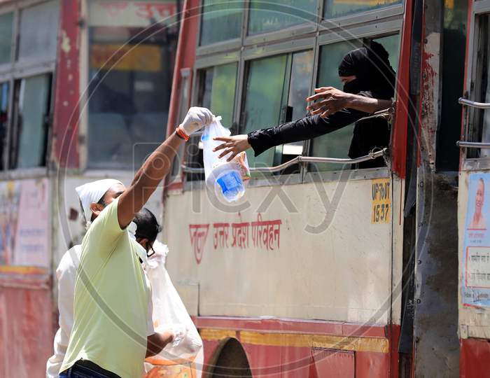 People Distribute Food Packets To Migrants  In A Bus Travelling To  Their Native Places During Extended Nationwide Lockdown Amidst Coronavirus Or COVID-19 Pandemic In Prayagraj, May 25, 2020.