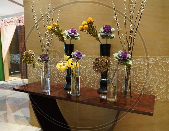 Black And Glass Vases With Flowers Inside Are Put On The Antique Table For Interior Decoration In A Hotel Lobby. They’Re Decorative Items For Vintage Classic Design In House, Hotel, Restaurant.