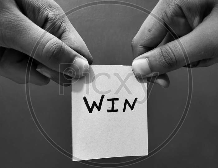 Hands holding a paper card with the word WIN