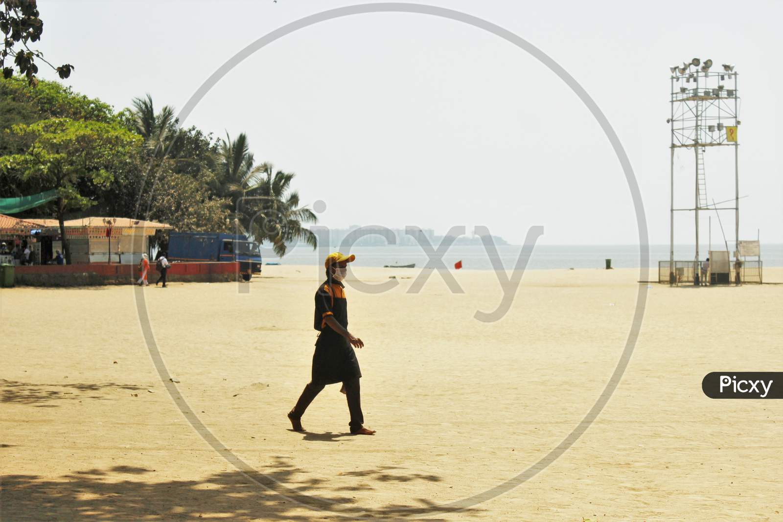 A man wearing a protective mask walks on deserted Girgaon Chowpatty after the Maharashtra state government banned public gatherings to avoid the spreading of the coronavirus, in Mumbai, India on March 18, 2020.