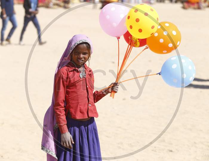 An Indian Girl Child Selling Balloons in Jaisalmer Desert Festival, Rajasthan, India