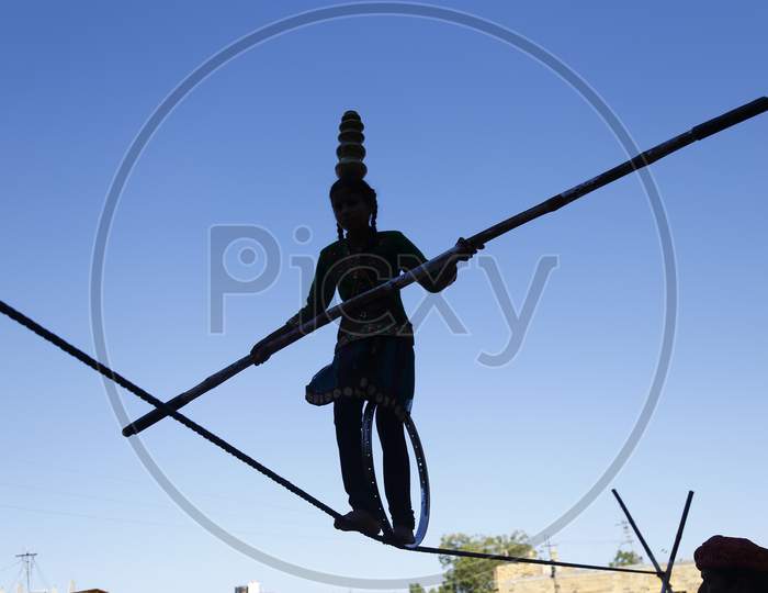 An unidentified Indian girl performs street acrobatics by walking the rope during the Desert Festival in Jaisalmer, Rajasthan, India.