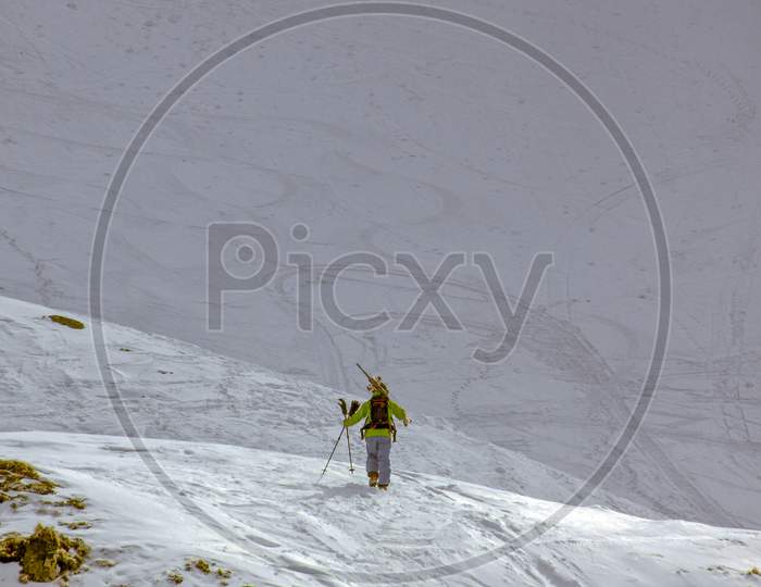 Skier Walking Uphill On Snow Mountain