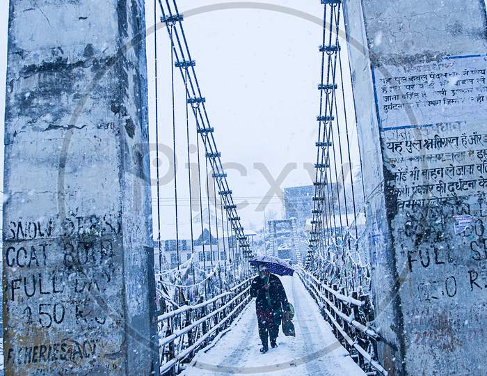 Manali, India - Jan 22, 2019: Heavy Winter Snow Fall, A Person Walking Alone With Black Umbrella On The Bridge, Wide Angle Shot - Image