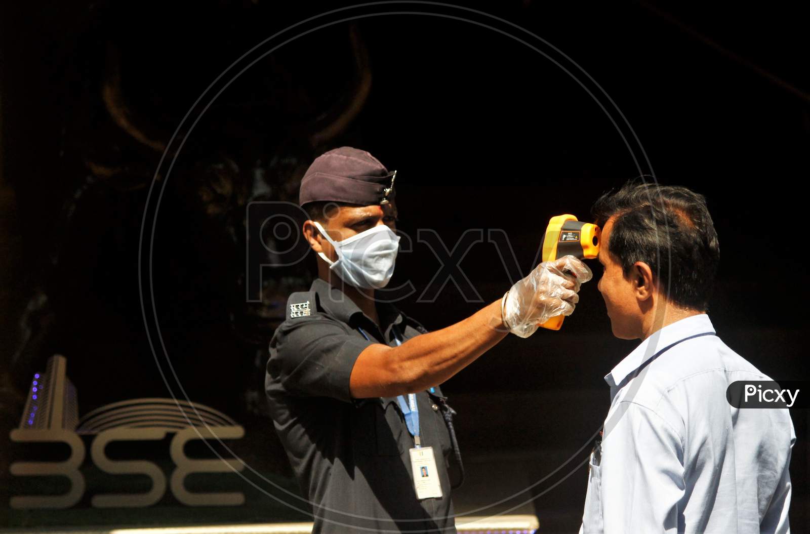 A security official scans a visitor with an infrared thermometer to check his temperature as a precautionary measure against coronavirus outside the Bombay Stock Exchange (BSE) in Mumbai, India March 16, 2020.