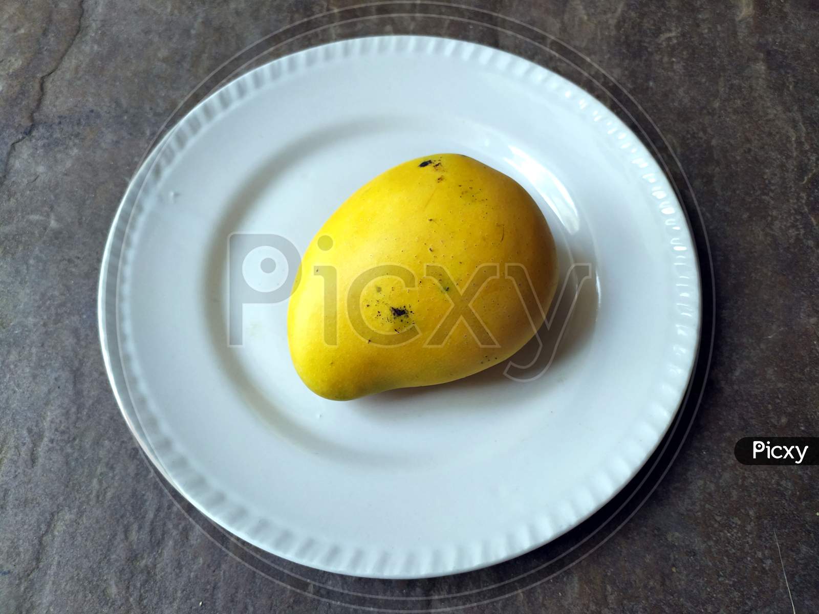 fresh sweet yellow mango put in a white plate on stone background