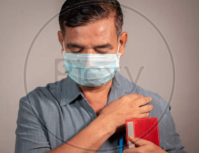 50'S Man Holding Bible And Praying God With Medical Face Mask Wearing To Protect From Covid-19 Or Coronavirus Pandemic - Concept Of Hope, Peace During Tough Quarantine Times.