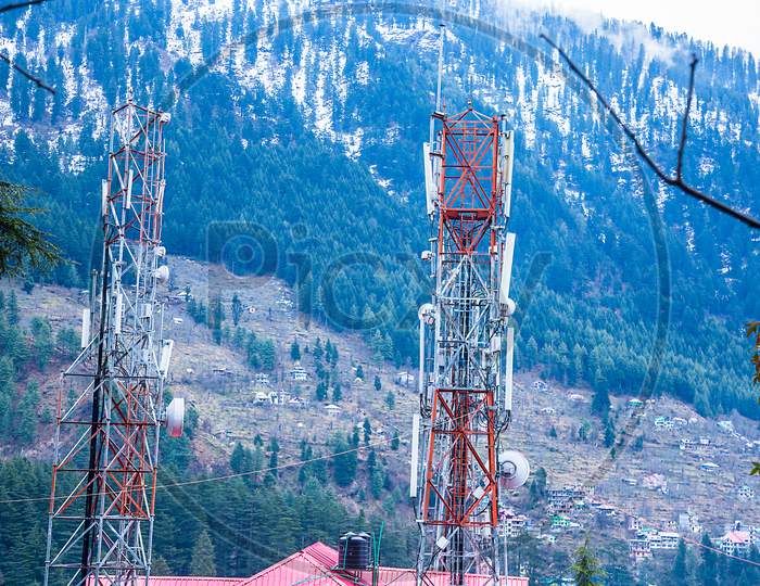 Telecommunication Tower At Mountain Range Covered With Trees And Snow In The Background, Mobile Phone Telecommunication Radio Antenna Tower. - Image