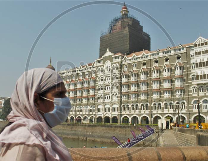 A woman wearing a protective mask as a precautionary measure against coronavirus walks outside The Taj Mahal Palace, in Mumbai, India on March 17, 2020.