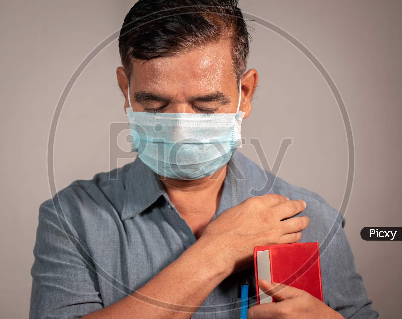 50'S Man Holding Bible And Praying God With Medical Face Mask Wearing To Protect From Covid-19 Or Coronavirus Pandemic - Concept Of Hope, Peace During Tough Quarantine Times.