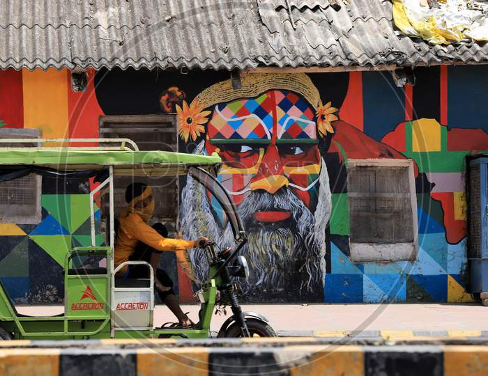 A Man drives past a mural On A Hot Weather day In Prayagraj, May 26, 2020.